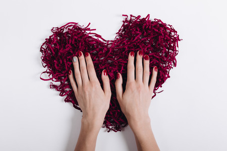 Red decorative heart and woman's hands with a manicure, top viewの写真素材