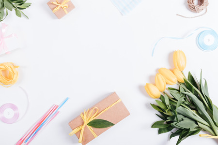 Bouquet of yellow tulips, boxes with gifts, ribbons and rope on a white table, top view, space for textの写真素材