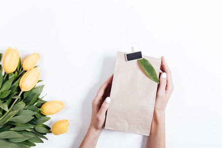 Yellow tulips and woman's hands with gift boxes on a white background, top viewの写真素材
