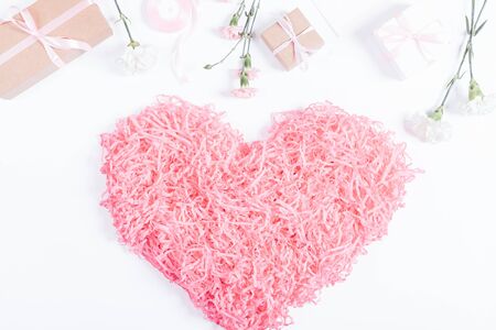 Decorative pink heart, boxes with gifts and flowers lie on a white background, top viewの写真素材