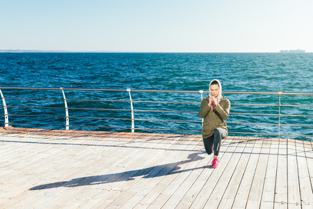 Spring morning on the beach young woman doing sports exercises against the sea, wide angleの写真素材