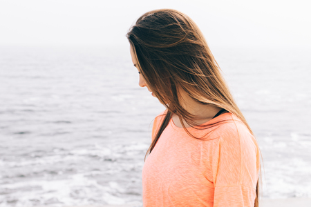 Beautiful young brunette with long hair against the sea, close-upの写真素材
