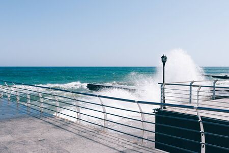 Waves break on the pier on a sunny day, windy weatherの写真素材