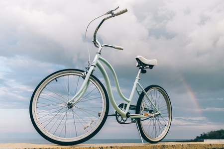 Vintage women's bike on the background of the sea and a rainbow on the beachの写真素材