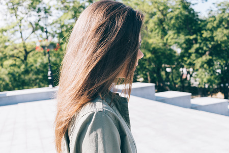 Young woman with long brown hair walks in the park in summer, close-upの写真素材