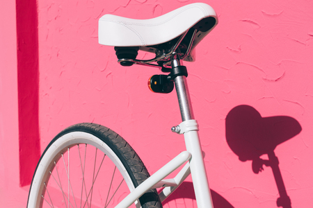 Close-up of a female city bicycle seat against a pink wall backgroundの写真素材