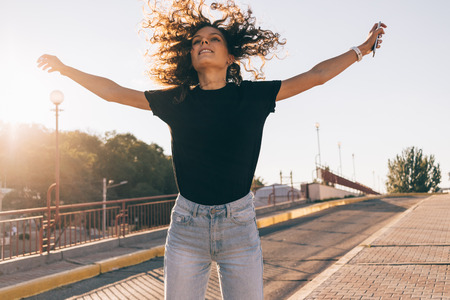 Happy girl with curly brown hair in the city in summerの写真素材