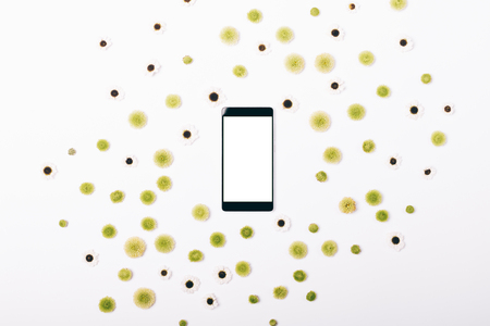 Mobile phone and pattern of flowers on a white table top viewの写真素材