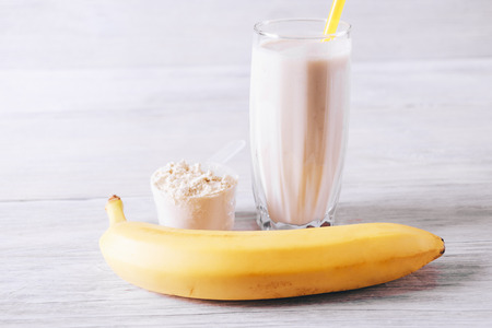 Sports nutrition with protein and banana on white wooden table close-upの写真素材