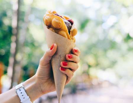 Close-up of fast food in a female hand with red manicureの写真素材