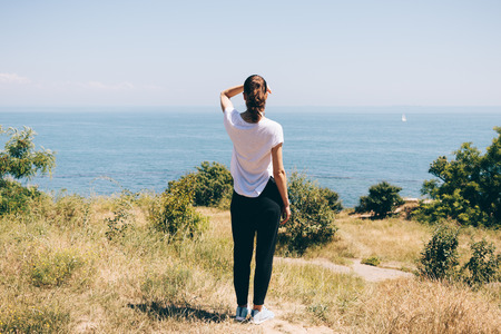 Young woman on the beach looking at the sea, view from the backの写真素材