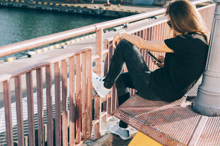 girl in jeans and a t-shirt using a mobile phone in the cityの写真素材