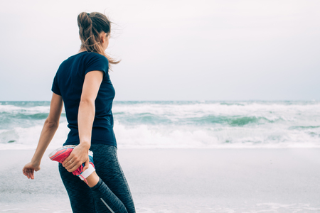 Young athletic woman doing stretching in the morning on the beachの写真素材
