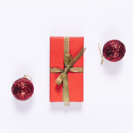 Top view of red gift box with golden ribbon and Christmas balls on white backgroundの写真素材