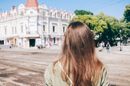 Young woman tourist with brown hair traveling through the old towns in the summer