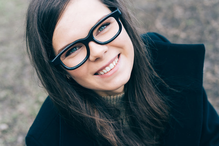 Young beautiful woman with glasses looks at the camera and smilesの写真素材