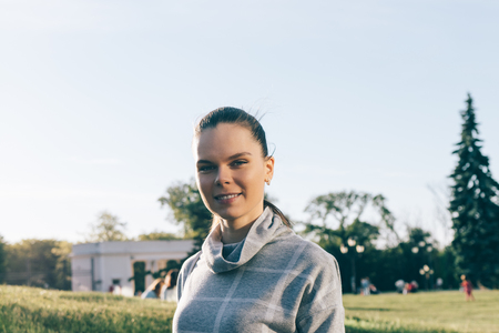 Portrait of a young smiling woman in a green parkの写真素材
