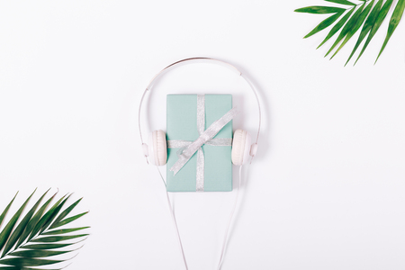 White headphones and a box with a gift near a green leaf, top viewの写真素材
