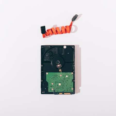 Hard drive and red cable on white table top view