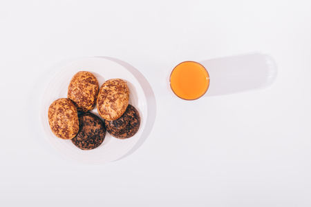 Cookies on a plate and a glass of juice on a white table top viewの写真素材
