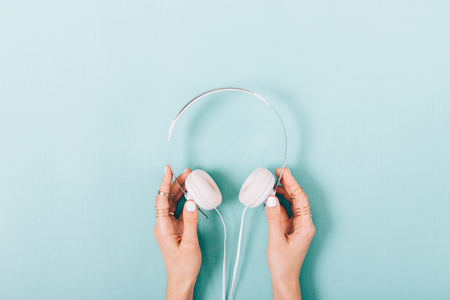 White headphones in female hands with a manicure on a blue background top viewの写真素材