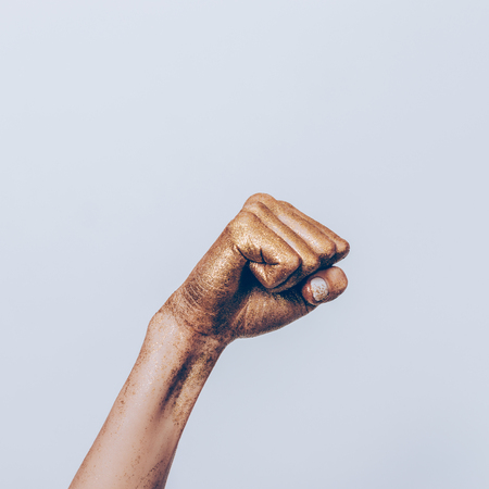 Golden female fist on gray background close-upの写真素材