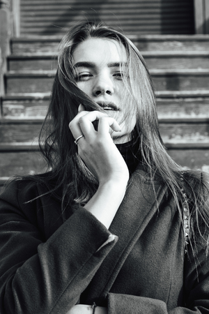 Vertical black and white portrait of a beautiful girl with long hair in a coatの写真素材