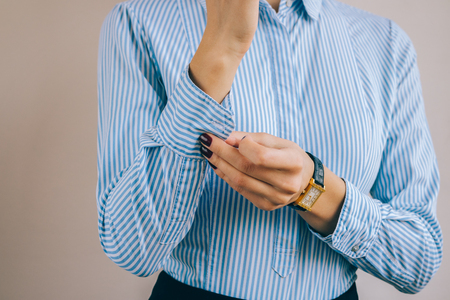 Cropped image of a woman buttoning up a shirt sleeve close-upの写真素材