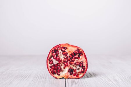 Half fresh red pomegranate on white table close-upの写真素材