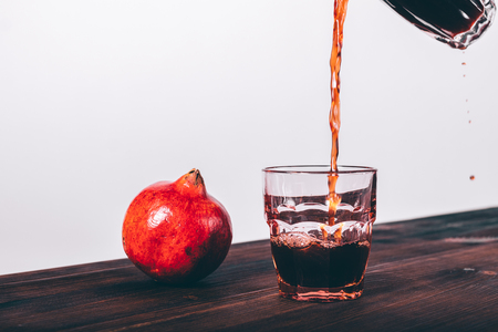 Juice is poured into a glass and a pomegranate fruit on a table close-upの写真素材