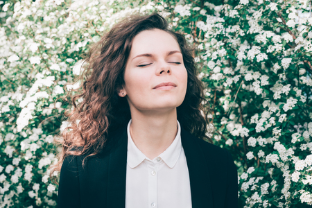 Portrait of a beautiful young woman with closed eyes on a spring flowers backgroundの写真素材