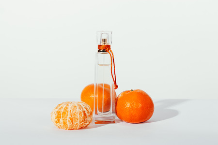 Bottle of toilet water and tangerines on a table on a white background closeupの写真素材
