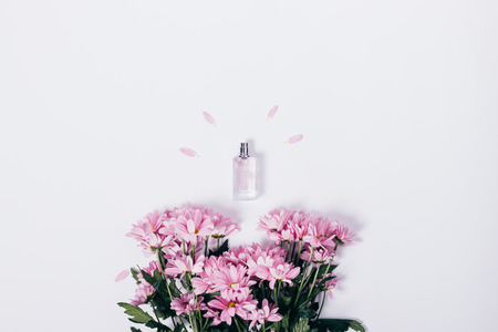 Lilac flowers and a small bottle of perfume on a white table top viewの写真素材
