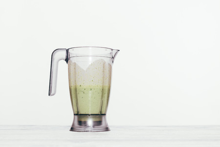 Blender jar with green smoothie inside. Minimal composition with fresh made healthy drink on white background with copy space.の写真素材