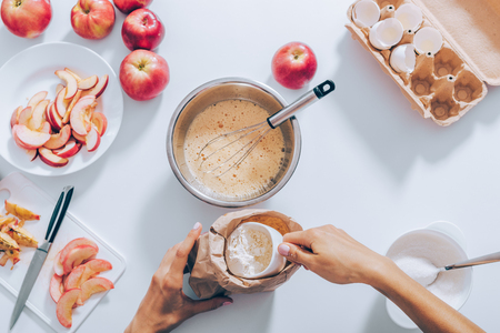 Top view woman measuring flour for dough to prepare apple pie. Flat lay composition of kitchen table with ingredients for cooking seasonal fruit cake.の写真素材