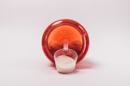 Protein powder from an open jar is poured into scoop. Special nutrition for athletes to build muscle mass.の写真素材