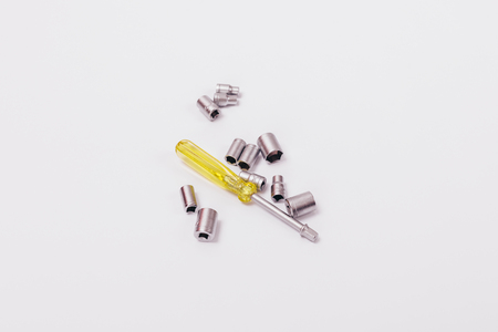 Screwdriver and attachments for wrench on white background. Composition of work tools.