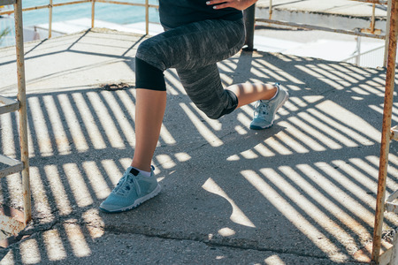 Athletic young woman doing lunges in the morning on the beach.の写真素材