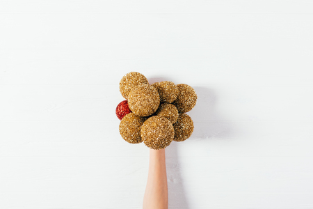 Creative flat lay of New Year decorations of gold and red color. Female hand holding bunch of Christmas balls on white background, top view.の写真素材