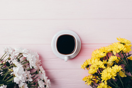 Floral composition of espresso on pink wooden table, top view. Flat lay arrangement of black coffee and bouquets of fresh flowers, copy space.の写真素材