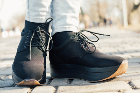 Woman's legs in black shoes on flat platform on street, close-upの写真素材