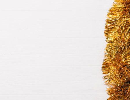 Flat lay composition of golden Christmas tinsel garland on white wooden table with copy space, top view.の写真素材