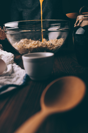 Cropped image of woman at table cooking pie dough, pouring yolks into flour with butter in large...
