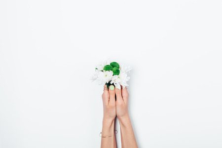 Small bouquet in female's hands with green manicure on white background. Woman holding fresh flowers.の写真素材