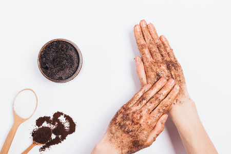 Female's hands apply massaging moves cosmetic scrub of ground coffee, sugar and coconut oil, top view on white table.の写真素材