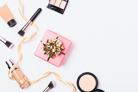 Festive flat layout of gift box and cosmetic products on white background with copy space.の写真素材