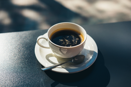 Cup of fresh coffee served on table in cafe near window at sunny day, close-up.の写真素材