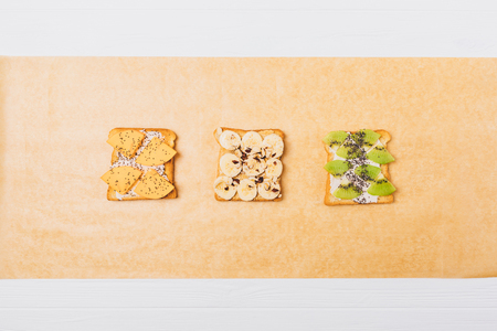 Flat lay composition ideas for tasty healthy breakfast. Different fruit toasts on cooking paper, top view.の写真素材