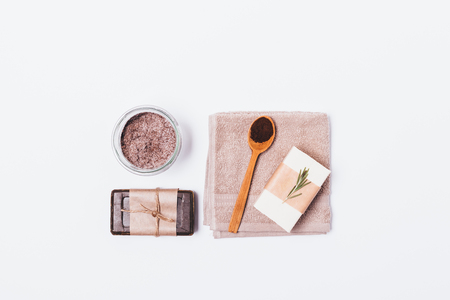 View from above natural coffee cosmetics for cleansing and exfoliating skin at home. Organic soap, scrub of ground coffee and sea salt with rosemary oil on white background, flat lay.の写真素材