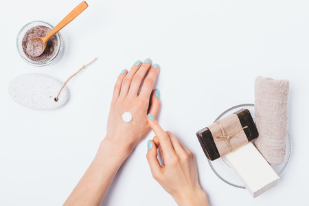 Woman's hands with blue manicure apply cosmetic cream next to beauty products for skin cleanse and exfoliation, flat lay.の写真素材